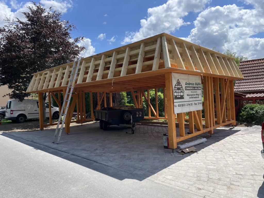Holz-Carport im Rohbau mit umlaufender Attika und großzügiger Einfahrt