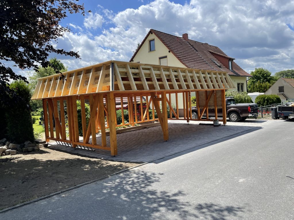 Holz-Carport im Rohbau mit umlaufender Attika und offener Seitenkonstruktion